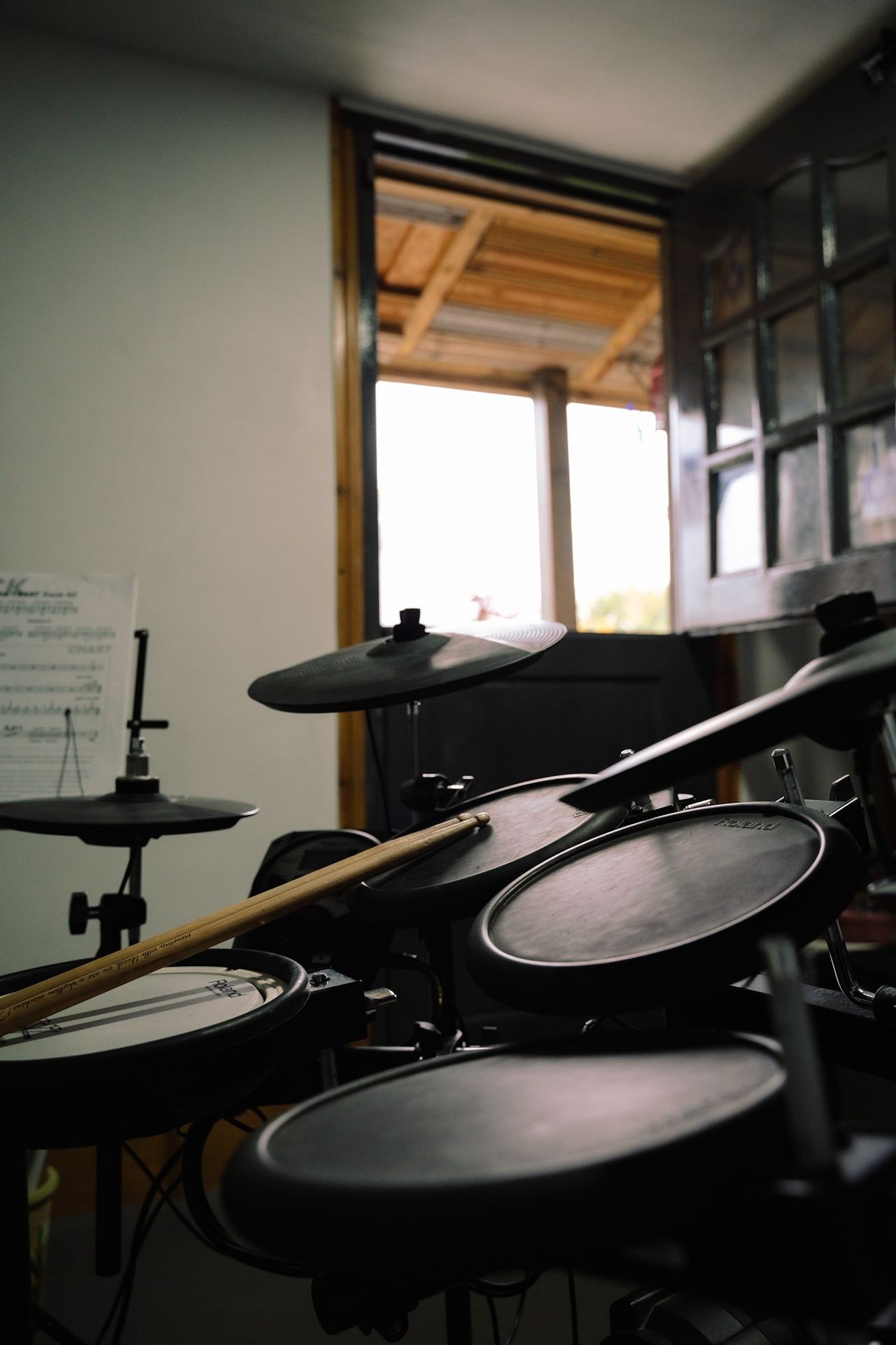 Electronic drum set in a room with an open door, letting in natural light from outside.